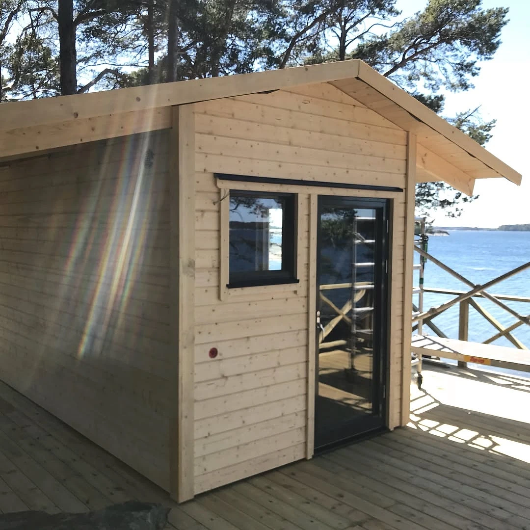 Träbastu med glasdörr på altan vid havet